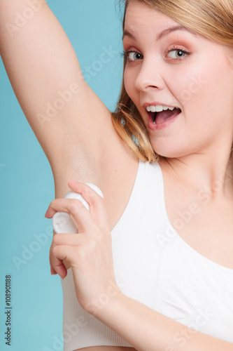 Girl applying stick deodorant in armpit.