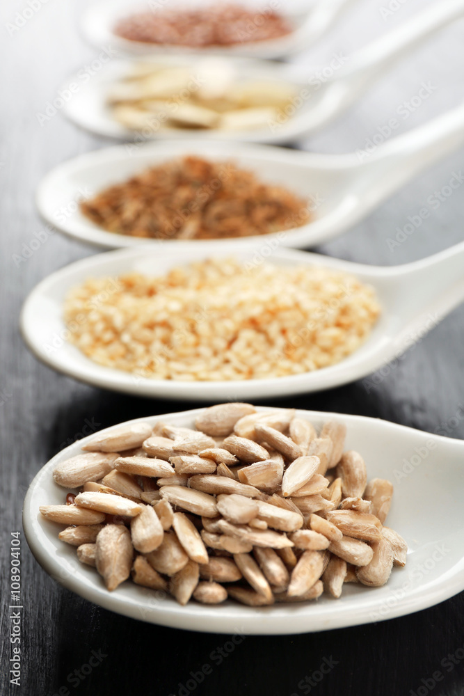 Different kinds of seeds in spoons on wooden table Different kinds of seeds in spoons on wooden table