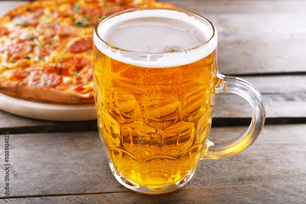 Tasty pizza and glass of beer are on wooden table, close up Tasty pizza and glass of beer are on wooden table, close up