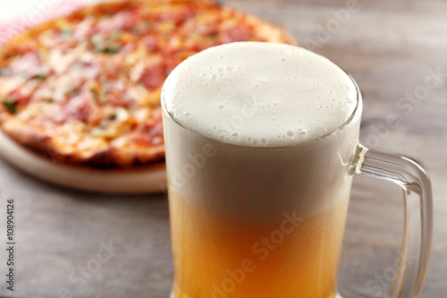 Tasty pizza and glass of beer are on wooden table, close up