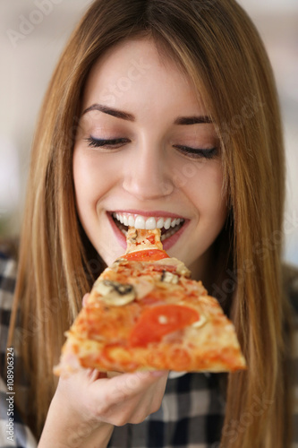 Happy young woman eating slice of hot pizza  close up