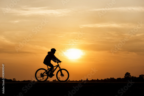 Silhouette of cycling on sunset background