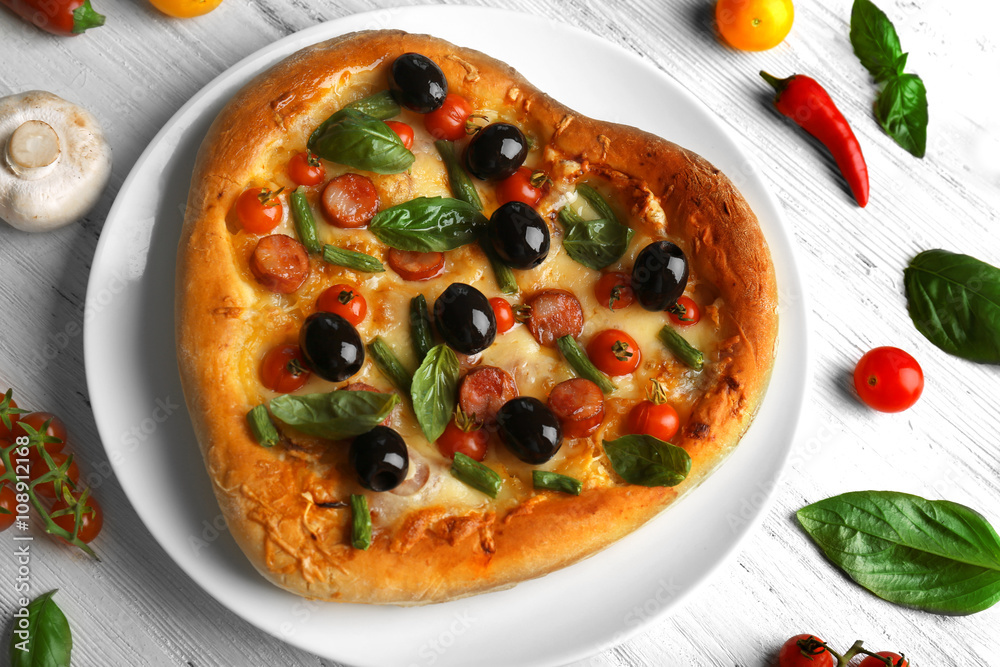 Fresh tasty heart shaped pizza decorated with vegetables and herbs on wooden background Fresh tasty heart shaped pizza decorated with vegetables and herbs on wooden background