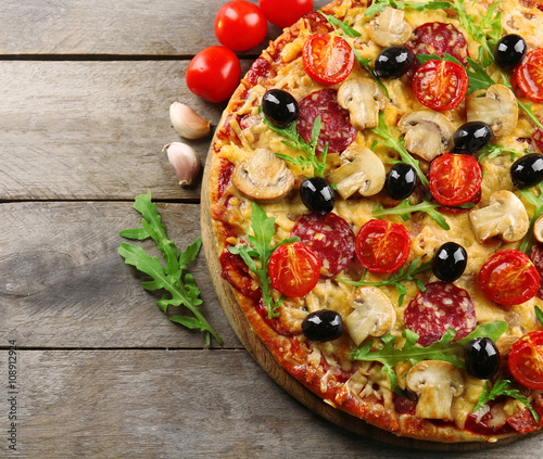 Delicious tasty pizza with ingredients on wooden table