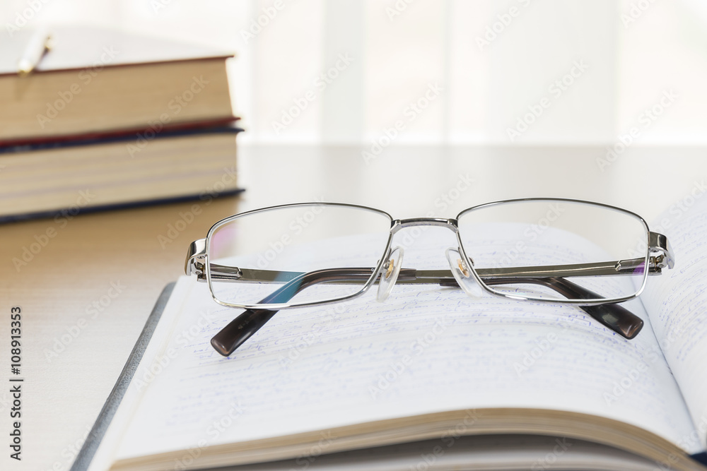 Eyeglasses put on notebook on wood table Eyeglasses put on notebook on wood table