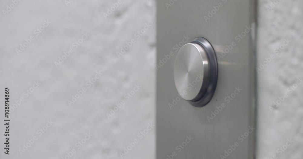 Man's finger reaches in and presses elevator button which lights up.  Macro view from the right.  Originally recorded in 4K.
