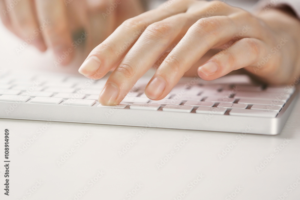Female hands using keyboard on white wooden table, close up Female hands using keyboard on white wooden table, close up