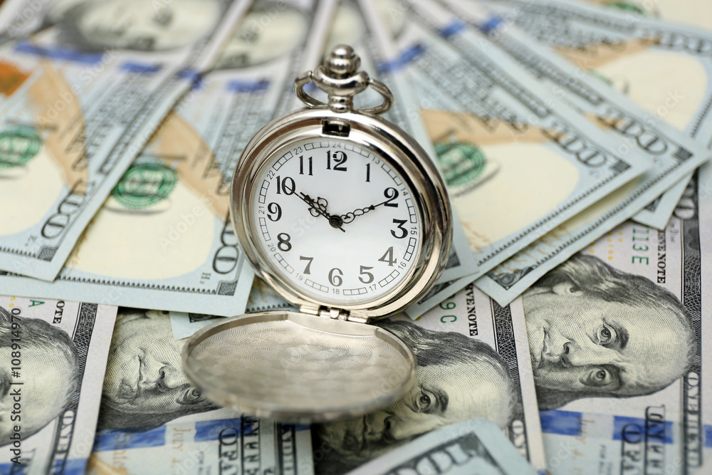 Time is money concept with pocket watch and dollars bills closeup Time is money concept with pocket watch and dollars bills closeup