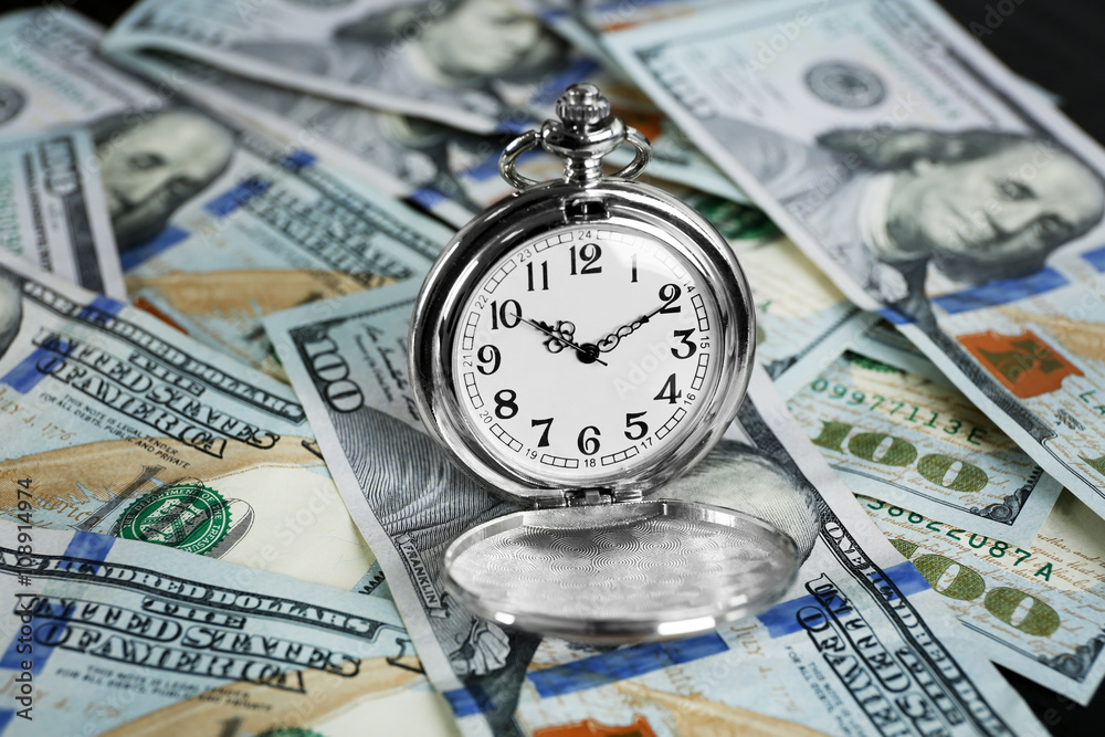 Time is money concept with pocket watch and dollars bills closeup Time is money concept with pocket watch and dollars bills closeup