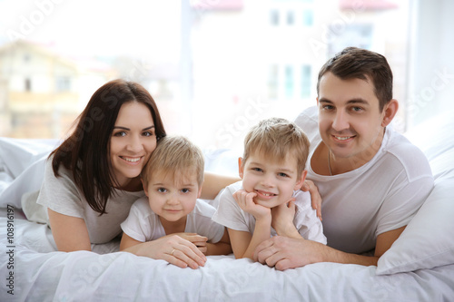 Happy family lying in bed o...