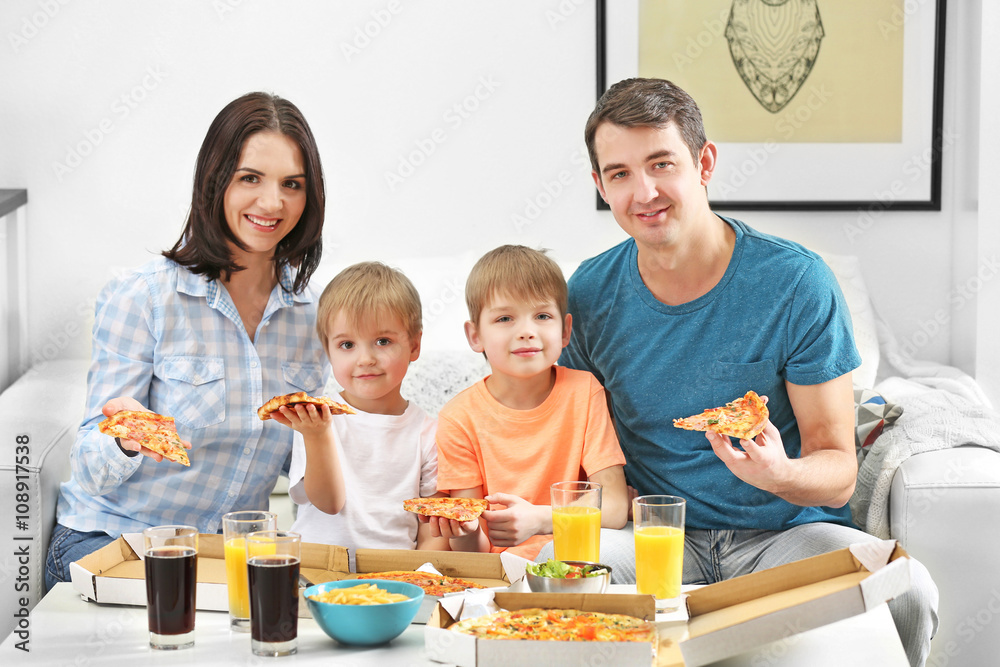 Happy family eating pizza on sofa all together Happy family eating pizza on sofa all together