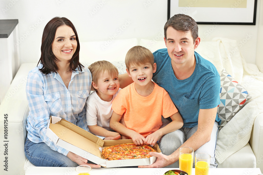 Happy family eating pizza on sofa all together