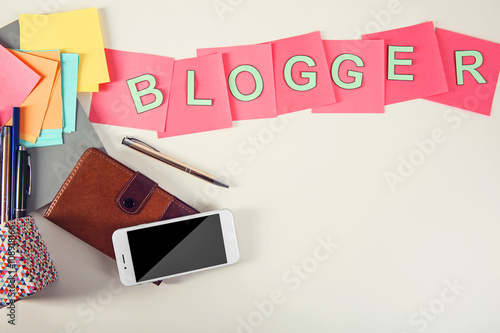 Blogger word on a table with phone and pocketbook.
