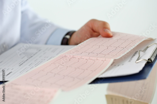 Male medicine doctor hands holding cardiogram chart
