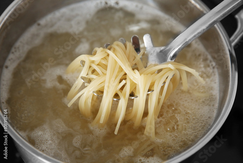 Spaghetti in spoon over pan closeup