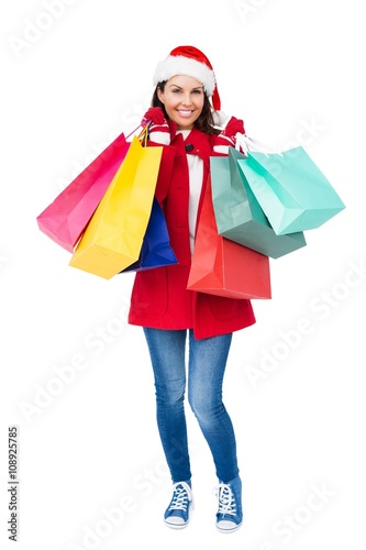 Beautiful brunette with santa hat holding shopping bags