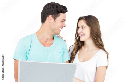Happy couple using a laptop on white background