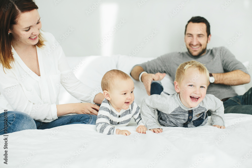 Parents with two small kids playing in bedroom Parents with two small kids playing in bedroom