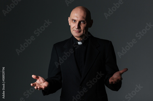 Catholic priest standing and doing welcome gesture
