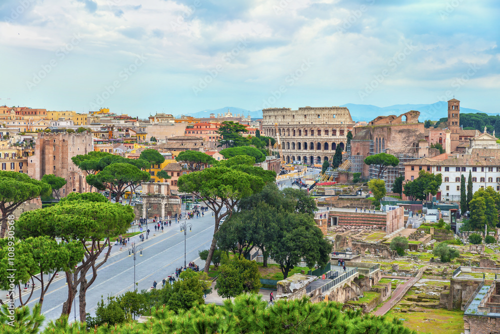 Aerial panoramic view on the Great Roman Colosseum (Coliseum, Colosseo, Flavian Amphitheatre.) and the Roman Forum in sunset time. Beautiful architectural and natural landscape. Rome. Italy. Europe.