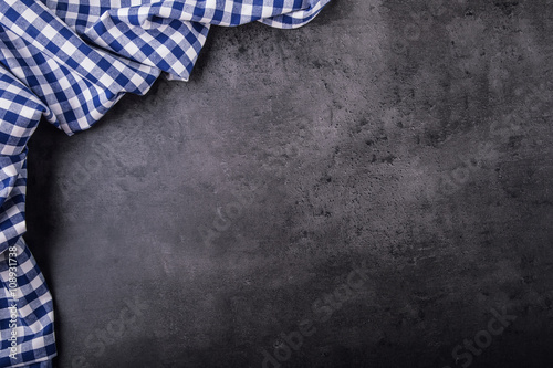 Top view of checkered kitchen tablecloth on granite - concrete - stone background. Free space for your text or products.