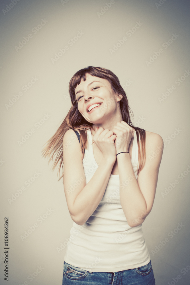 young woman is happy, her face expresses pleasure on a gray back young woman is happy, her face expresses pleasure on a gray back