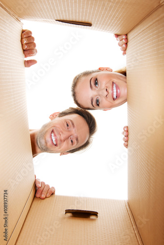Happy young couple opening a carton box and looking inside