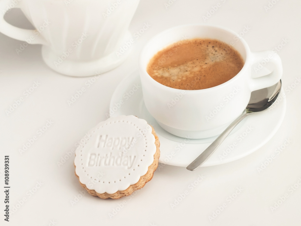 Close up of coffee cup and fondant covered cookie. Happy birthday decoration on top.