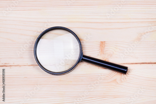 Magnifying glass on a wooden board.