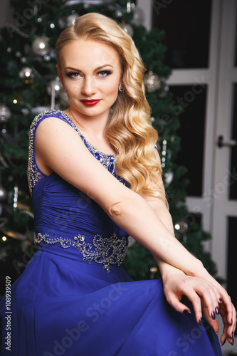 Portrait of gorgeous woman in luxury blue dress over christmas background