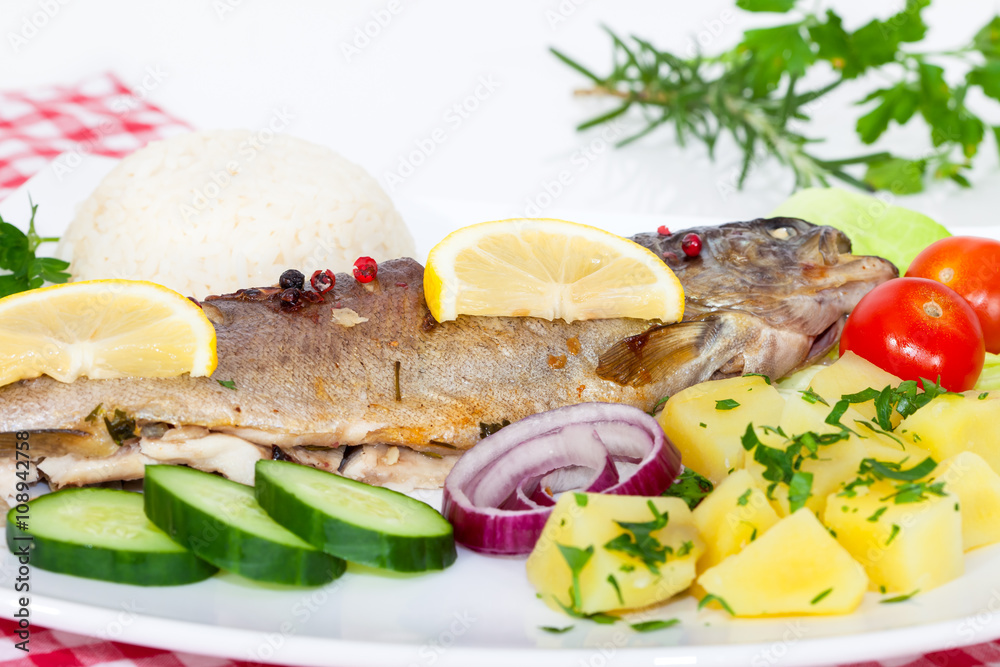 Grilled trout barbeque served with rice, potato, cucumber, tomato, onion and lemon