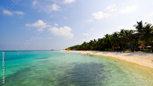 Beautiful beach with tropical plants of green palm trees blue clean atlantic ocean water and sandy coast in sunny summer.