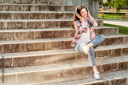 Beautiful hipster sitting on stairs in city park with earphones © Catalin Pop