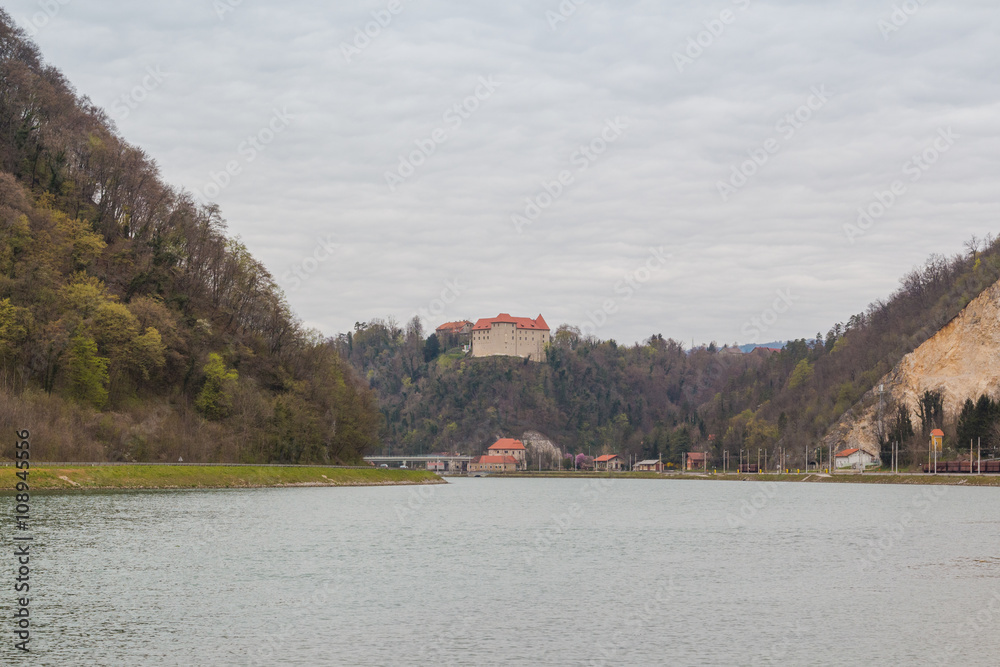 Wide Sava river flowing among hills and Rajhenburg castle on top of one of them.