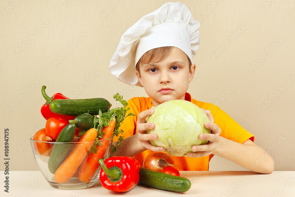Little boy chooses vegetables for salad at the table Little boy chooses vegetables for salad at the table