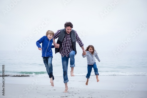 Family jumping at sea shore against clear sky