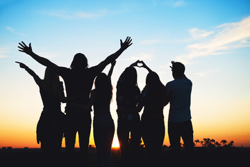 Group of people jumping outdoors; sunset 