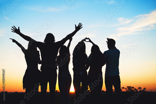 Group of people jumping outdoors; sunset 