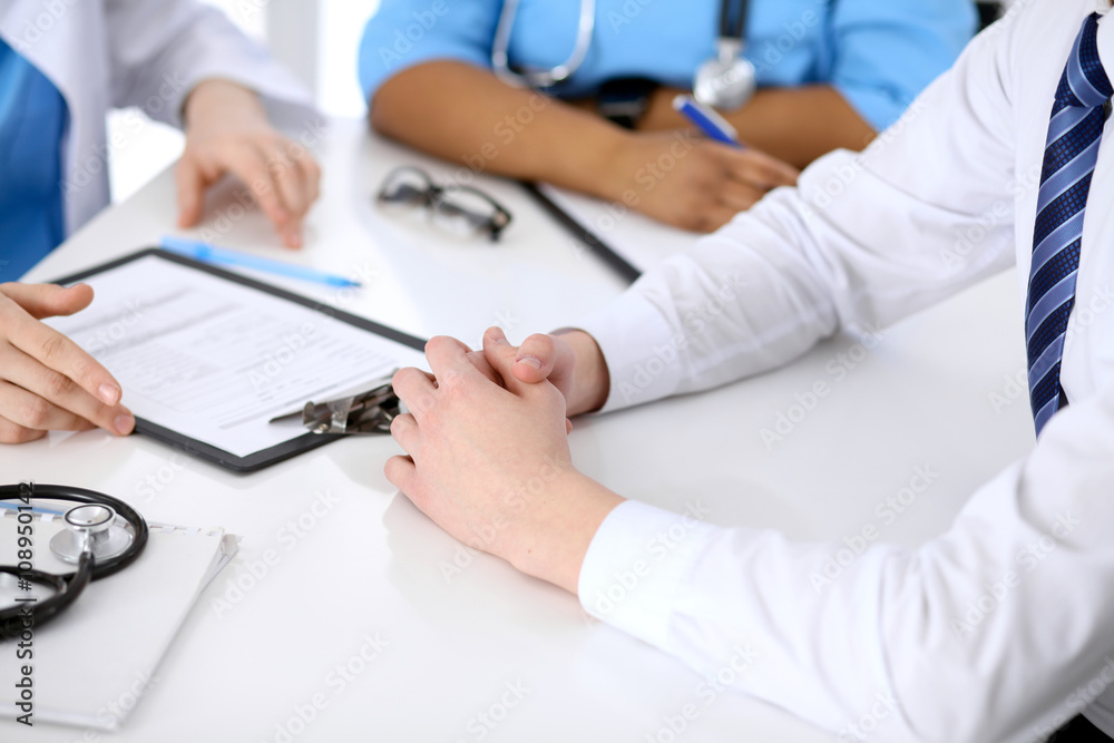 Two doctors and male patient discussing medical history at the table, close up Two doctors and male patient discussing medical history at the table, close up