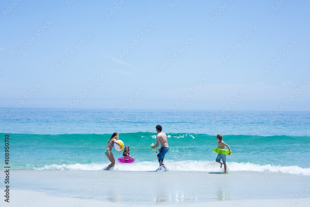 Family playing at sea shore against blue sky