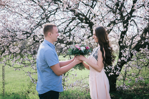 Portrait of a man hiding a flowers bouquet to surprise to a female