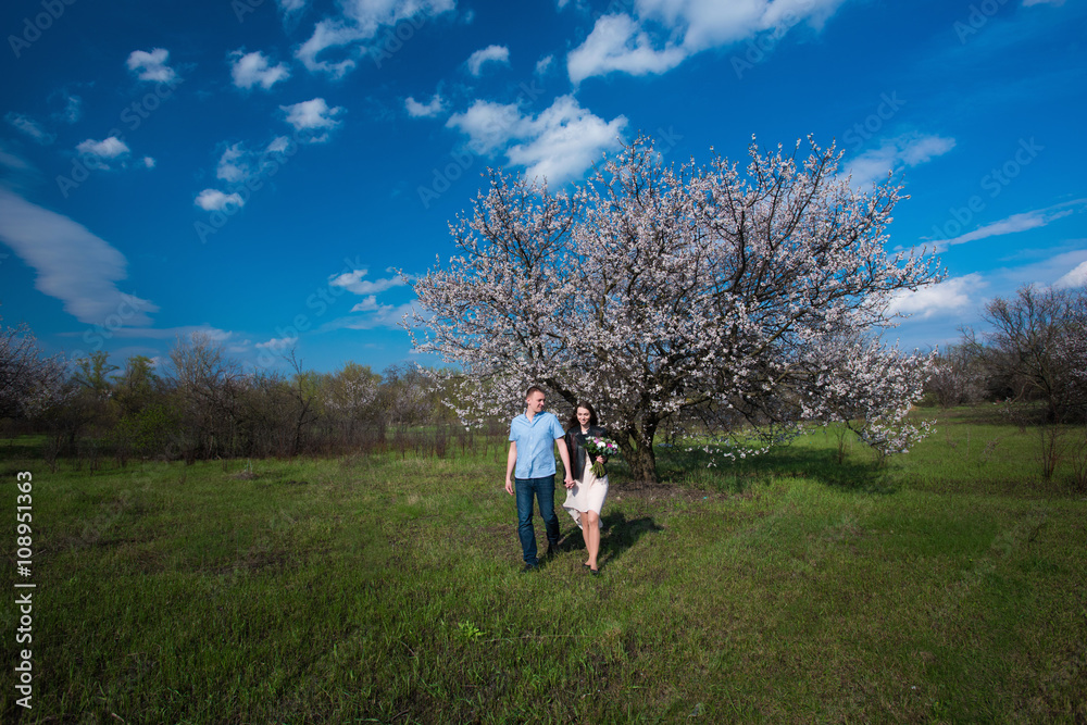 Happy couple running in bloom garden holding hand in hand on blue sky background,smile and have fun,lifestyle,yong Happy couple running in bloom garden holding hand in hand on blue sky background,smile and have fun,lifestyle,yong