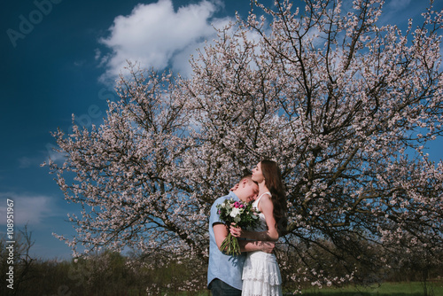 Young couple in love outdoor.Stunning sensual outdoor portrait of young stylish fashion couple posing in spring near blossom tree © tatyana_k