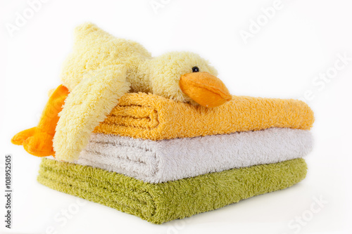 Three colorful towels with yellow plush duck isolated on white b