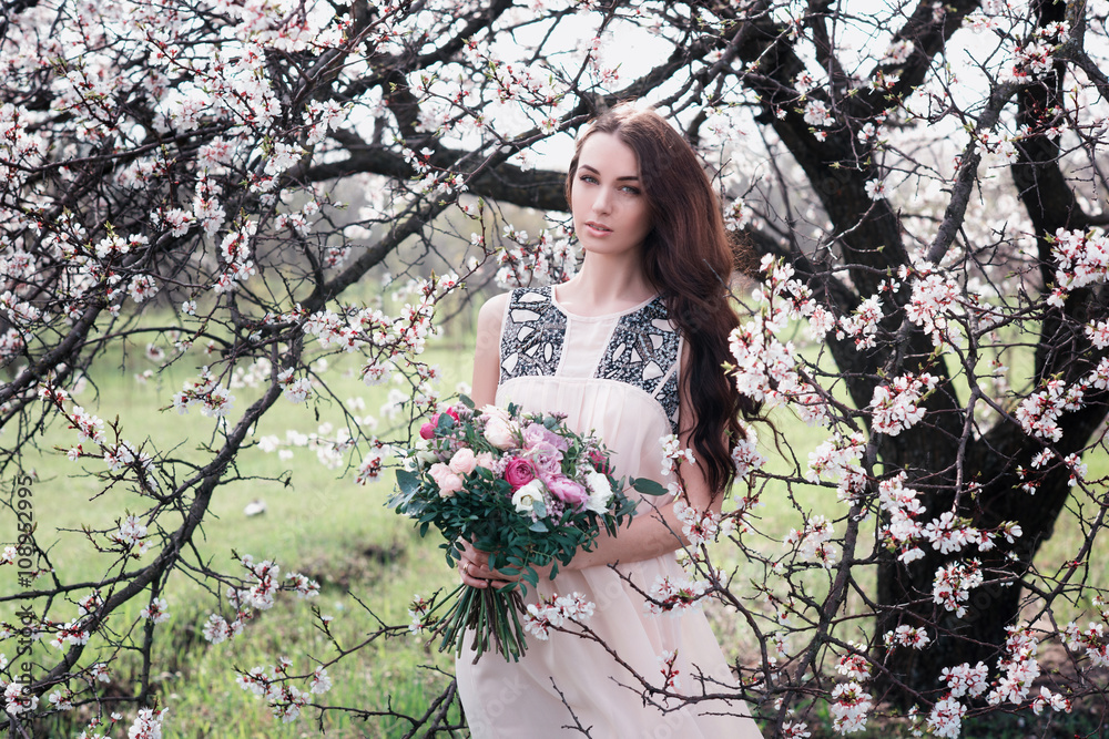 Woman in blooming trees. Woman with wedding bouquet in hands. Beautiful posing in a blooming apple garden.Spring mood. Young woman outdoors Woman in blooming trees. Woman with wedding bouquet in hands. Beautiful posing in a blooming apple garden.Spring mood. Young woman outdoors