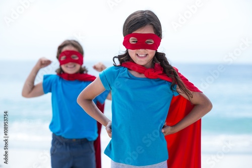 Siblings in superhero costume standing at sea shore