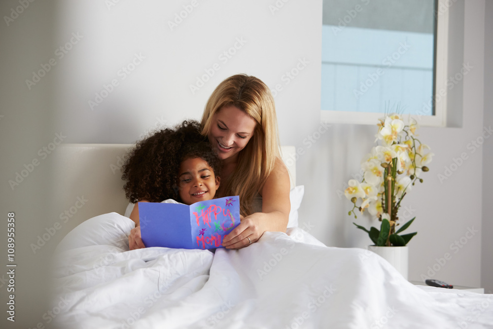 White mum and black daughter looking at card, full length White mum and black daughter looking at card, full length