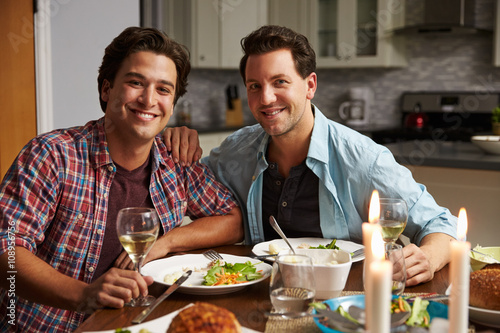 Male gay couple at home for a romantic dinner look to camera