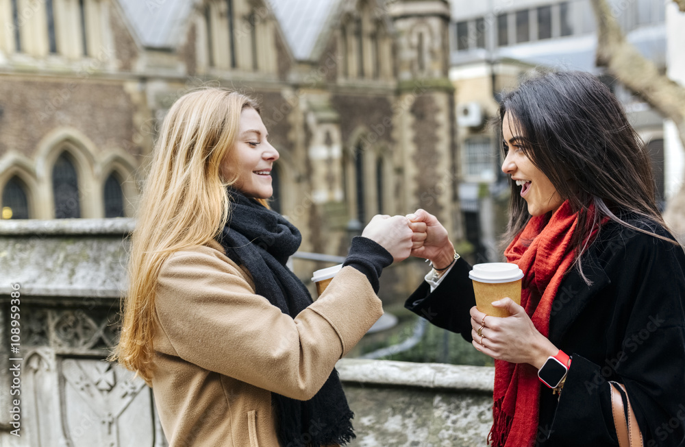 UK, London, Two friends exploring the city, drinking coffee in front of Southwark Cathedral UK, London, Two friends exploring the city, drinking coffee in front of Southwark Cathedral
