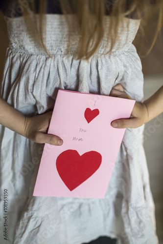 Girl with mother's day card behind back photo